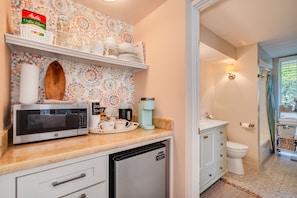 Efficient kitchen with microwave, coffee maker, toaster, and refrigerator, perfect for quick meal preparation.