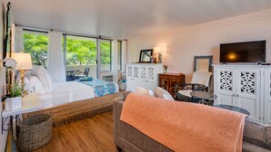 A well-lit room with a bed, a sofa, a TV, and a cabinet. - Diamond head charmer (Honolulu)