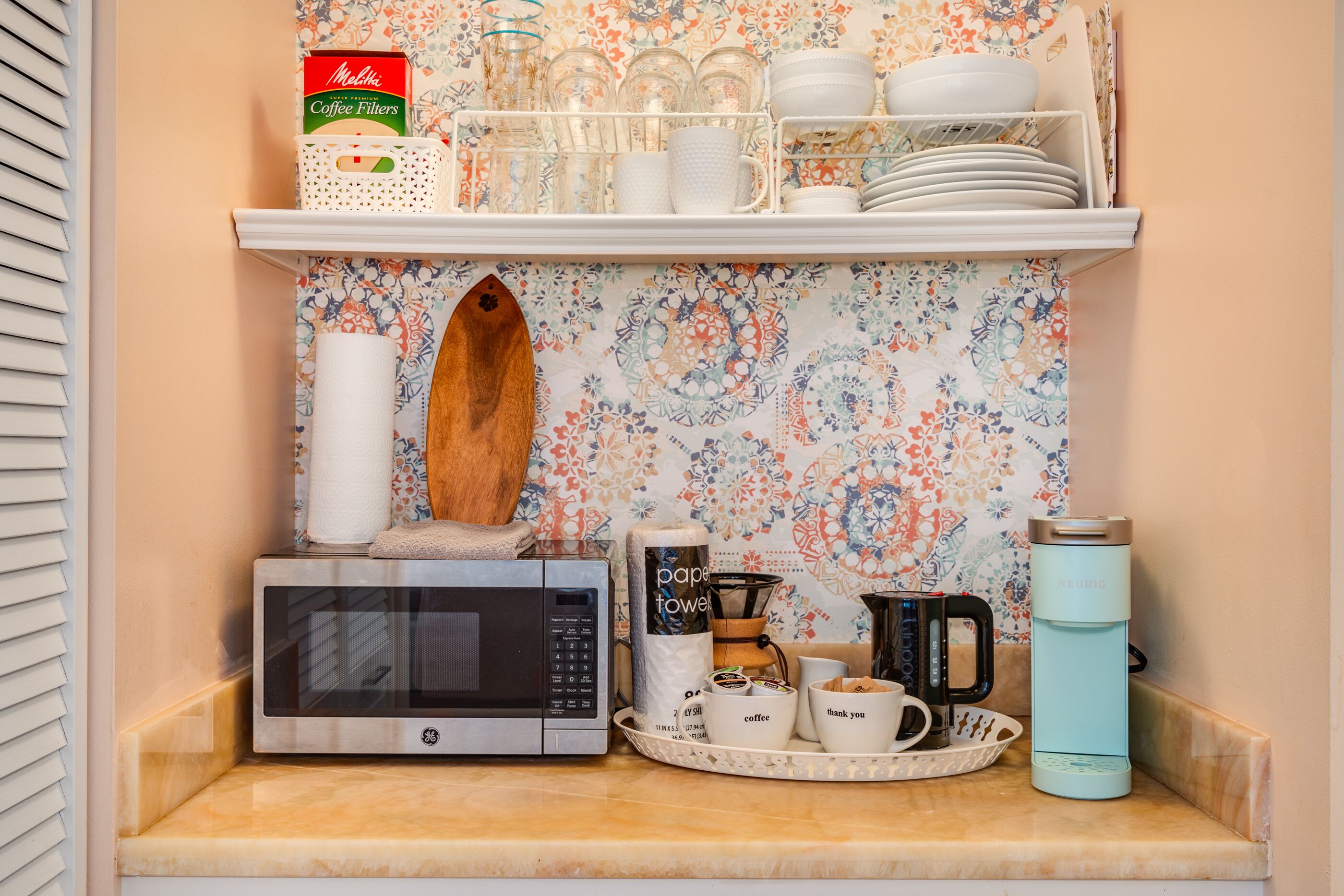 Una encimera de cocina con un microondas GE, una cafetera Keurig y una jarra de café.