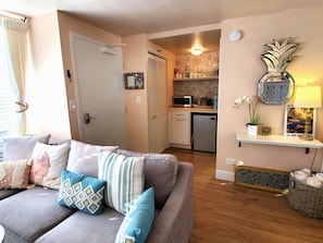 Relax in this inviting living room with a comfortable couch, kitchenette, and decorative touches.