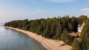 A coastal property with a beach, dense forest, and a house. - Sunsets, Sandy Beach and Seclusion; enjoy them all at this stunning lake house (Beaver Island)