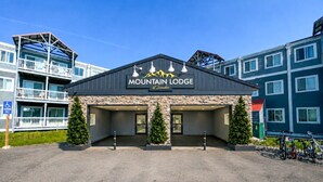 Een gebouw met de naam 'Mountain Lodge', met een gevel van natuursteen, twee ingangen en een parkeerplaats met fietsen.