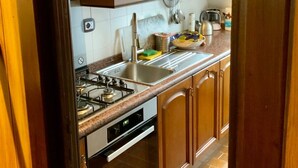 Een keuken met houten kastjes, een RVS spoelbak, een gasfornuis en een vaatwasser.