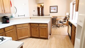 A kitchen with wooden cabinets, a white countertop, a coffee maker, and a ceiling fan. - Mille Lacs Lake Cabin, perfect, convenient  location for all outdoor activities! (Aitkin)