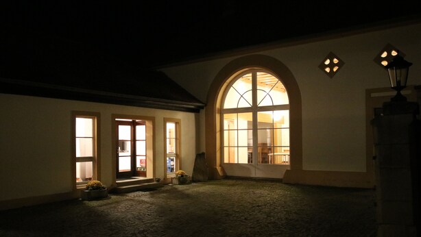 Ein Innenhof mit Kopfsteinpflasterboden, einem großen Rundbogenfenster und einem Lampenpfosten.