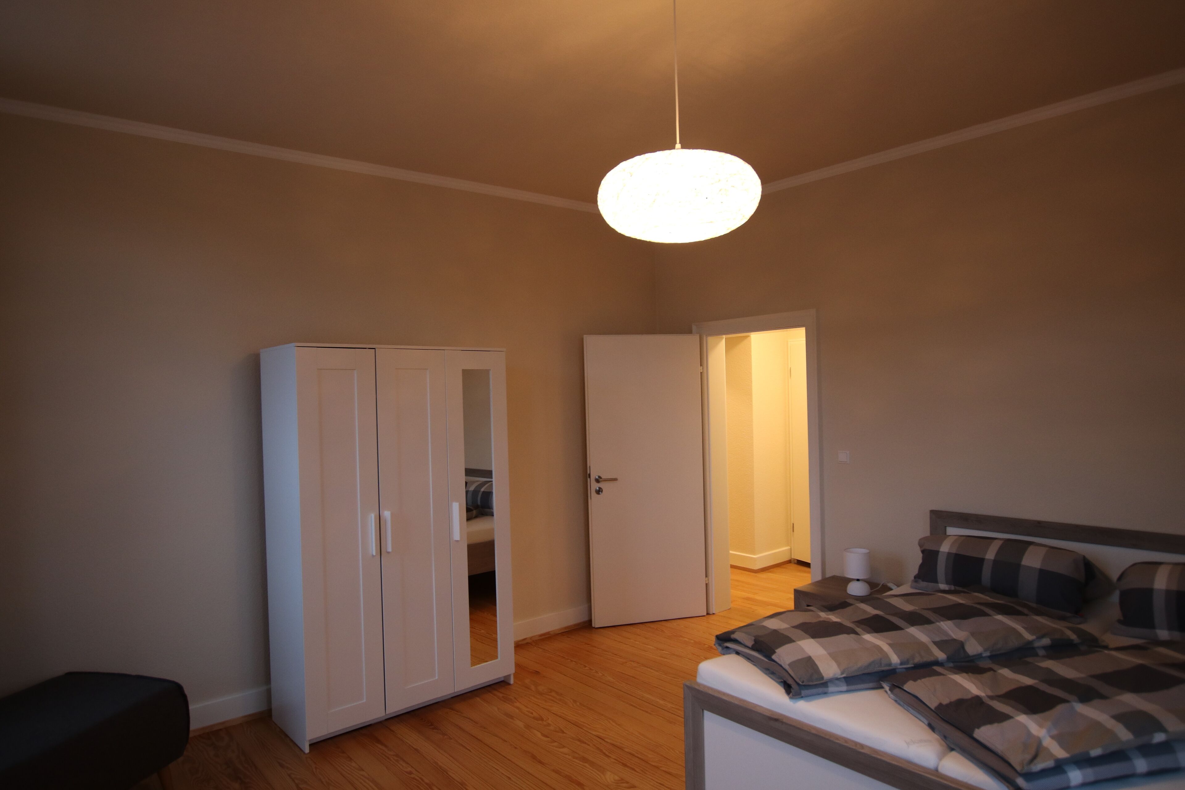 Ein Schlafzimmer mit einem Bett, einem Kleiderschrank und einer Tür zu einem anderen Raum.