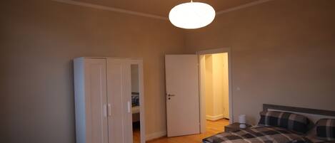 Ein Schlafzimmer mit einem Bett, einem Kleiderschrank und einer Tür zu einem anderen Raum.