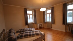 Ein Schlafzimmer mit einem Bett, einem Schreibtisch und zwei Fenstern.