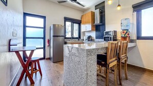 Eine moderne Küche mit Granit-Arbeitsplatten, Holzstühlen, einem Edelstahl-Kühlschrank und einem Deckenventilator.