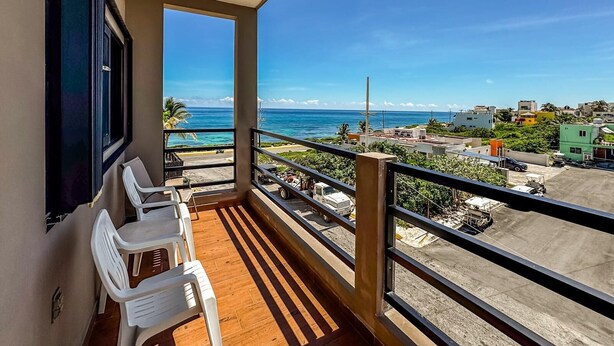 Een balkon met uitzicht op zee en een stadsbeeld.