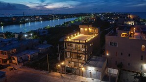 A multi-story building with balconies, a gated entrance, and a view of a river at dusk. - Ocean View 6 BR House Steps from Ocean! (Isla Mujeres)