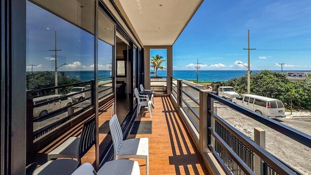 A balcony with a view of the ocean and parked vehicles. - Ocean View 6 BR House Steps from Ocean! (Isla Mujeres)
