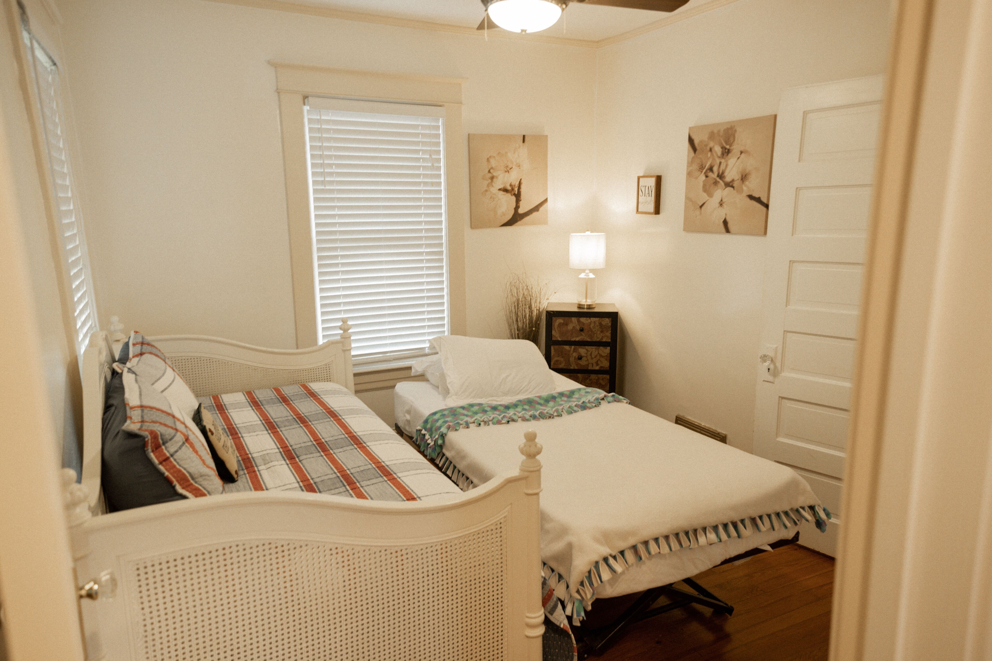 A bedroom with two beds, a nightstand, and a window with blinds.