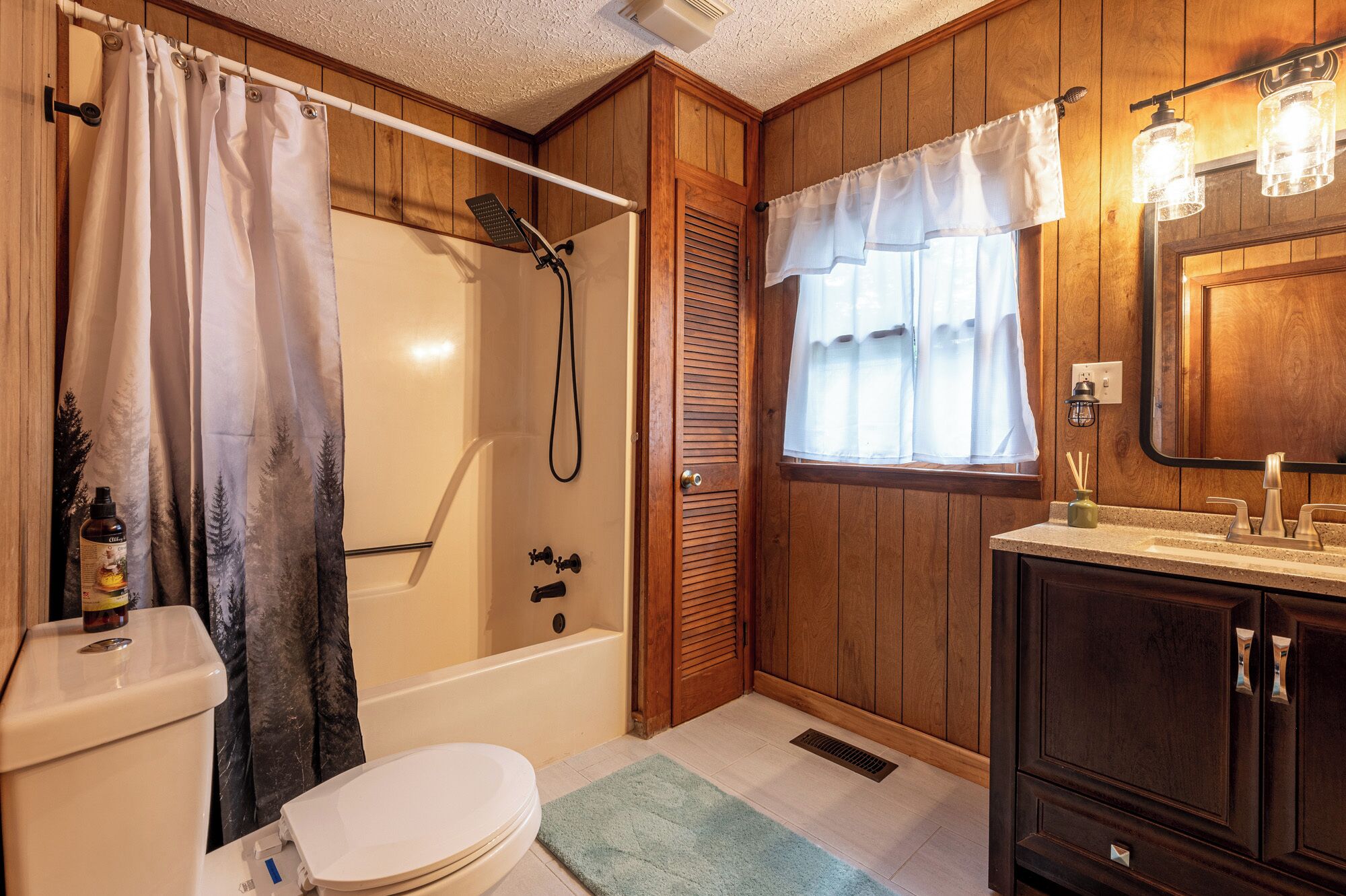 Une salle de bain avec douche, toilettes et lavabo.