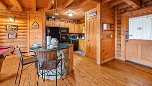 L’intérieur d’une cabane en bois comprend un coin repas, une cuisine et une porte donnant sur l’extérieur.