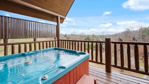 Une terrasse en bois avec un jacuzzi et une rambarde en bois.