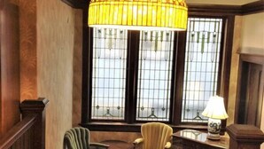 A room with a large stained glass window, a wooden staircase, and a table with chairs. - Petal Studio near DT, Free Parking (Victoria)