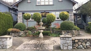 A two-story house with a stone facade, a stone staircase, and a well-maintained garden with a fountain. - New 2 Bedroom Suite Fairfield Heritage Manor, Free Parking (Victoria)