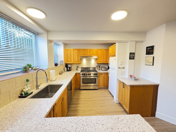 A modern kitchen with wooden cabinets, stainless steel appliances, and granite countertops.