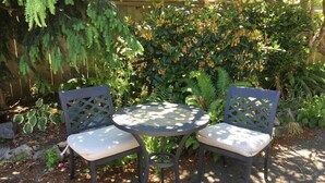 A round table with two chairs in a garden setting. - New 2 Bedroom Suite Fairfield Heritage Manor, Free Parking (Victoria)
