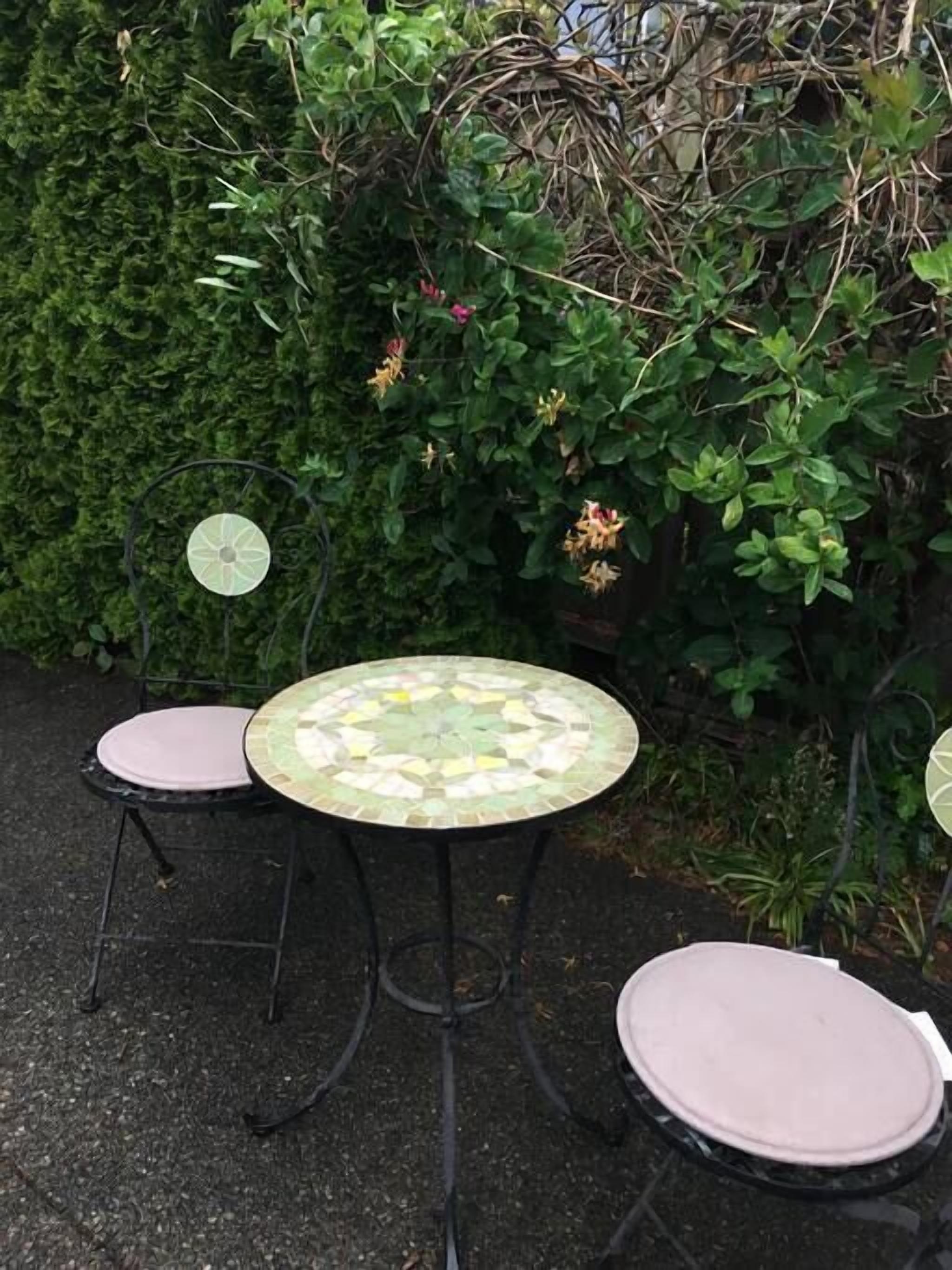 A round table with a mosaic top and a single chair.