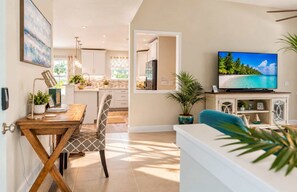 A modern living room with a TV, a dining area, and a kitchen. - 577 SunnyDaze | Private Heated Pool | Walk 2 Beach (Naples)