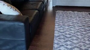 Una sala de estar con un sofá de cuero oscuro, un sofá de color claro y una alfombra estampada.