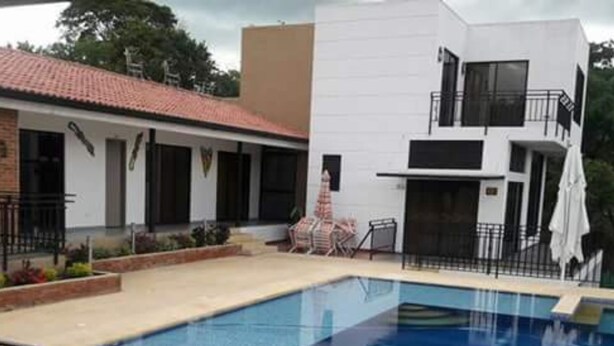 Piscina con barandilla negra, rodeada por un patio con sillas y una mesita.