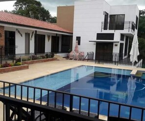 A swimming pool with a black railing, surrounded by a patio area with chairs and a small table. - Casa Vacacional Con Piscina en La Mesa (La Mesa)