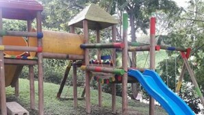 Un parque infantil con tobogán, estructuras para escalar y un pequeño refugio.