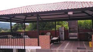 Un espacio al aire libre cubierto con una parrilla, asientos y un refrigerador.