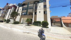 Un immeuble résidentiel à plusieurs étages, doté de balcons, d’une entrée sécurisée et d’une allée pavée.