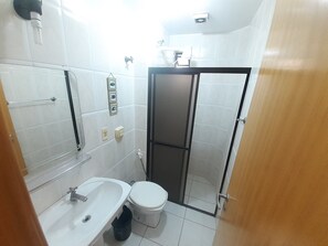 Une salle de bain de taille réduite, avec un lavabo blanc, des toilettes et un espace douche.