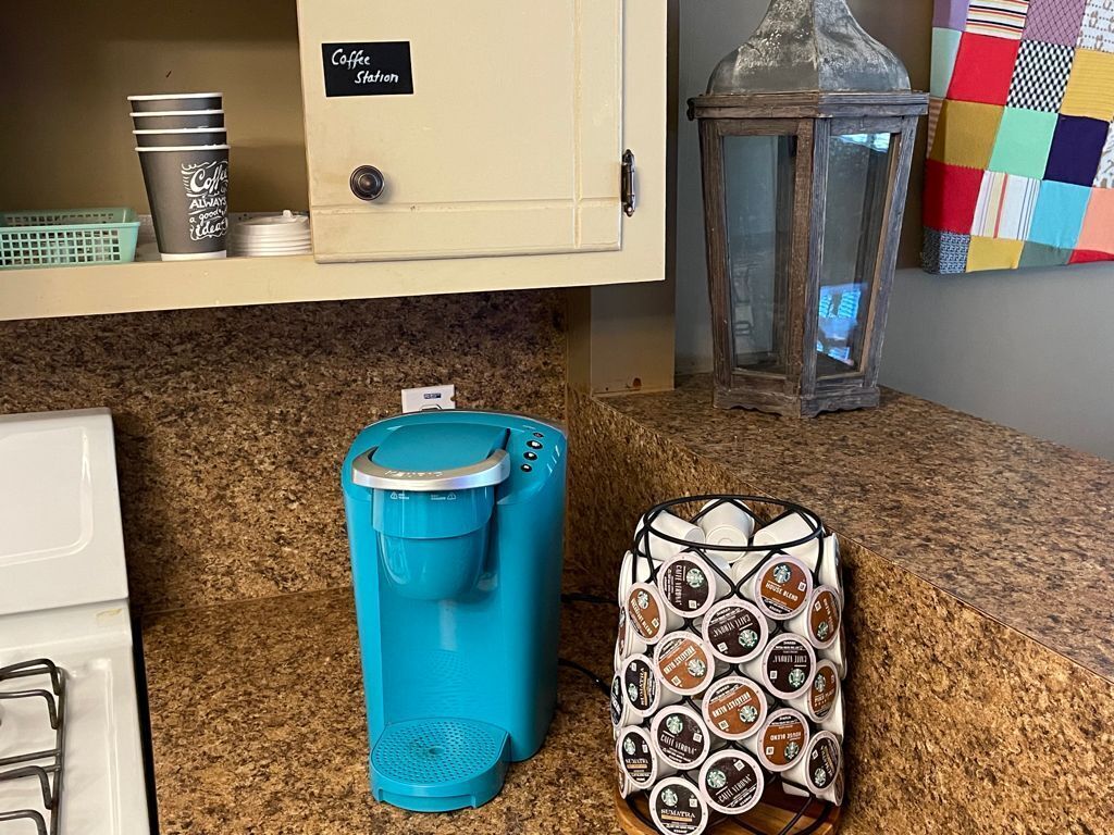 Una cocina con estación de café, cafetera y cesta de cápsulas de café.