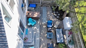 Une terrasse avec des meubles d’extérieur, un foyer et un espace jardin agrémenté de plantes et d’une clôture.