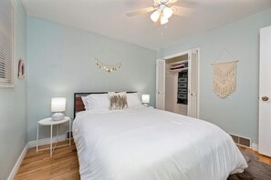 A bedroom with a bed, bedside tables, a ceiling fan, a wardrobe, and a macrame wall hanging. - MidCentury Modern 3BR 2BA + Hot Tub in College District  (Caldwell)