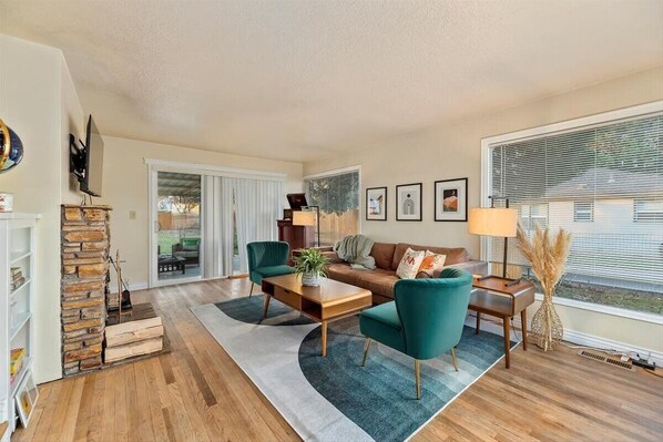 A modern living room with a sofa, two armchairs, a coffee table, and a fireplace.