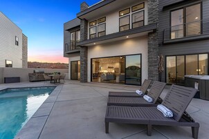 A modern two-story house with a swimming pool, outdoor seating, and a hot tub.