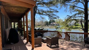 Una terraza de madera con mobiliario de mimbre y vistas a un lago.
