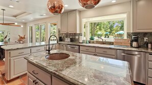 Una cocina moderna con encimeras de granito, electrodomésticos de acero inoxidable e iluminación colgante.