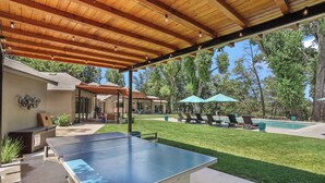 Un espacio al aire libre con mesa de ping pong, sillones de descanso y piscina.