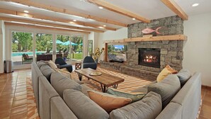 Un amplio salón con chimenea de piedra, un sofá grande y una mesa de comedor.
