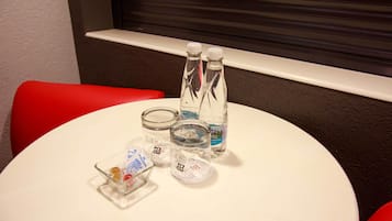 A round white table with two clear bottles of water, a small glass jar, and a glass container with a lid.
