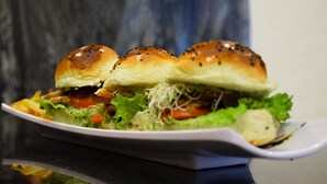 A sandwich with sesame seed buns and lettuce on a white plate. - Hotel Passion Secrets Villas & Suites (Toluca)