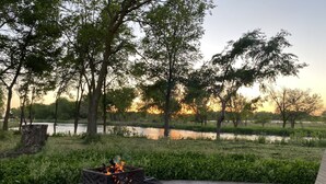 Un patio con una chimenea, rodeado de árboles y una masa de agua.