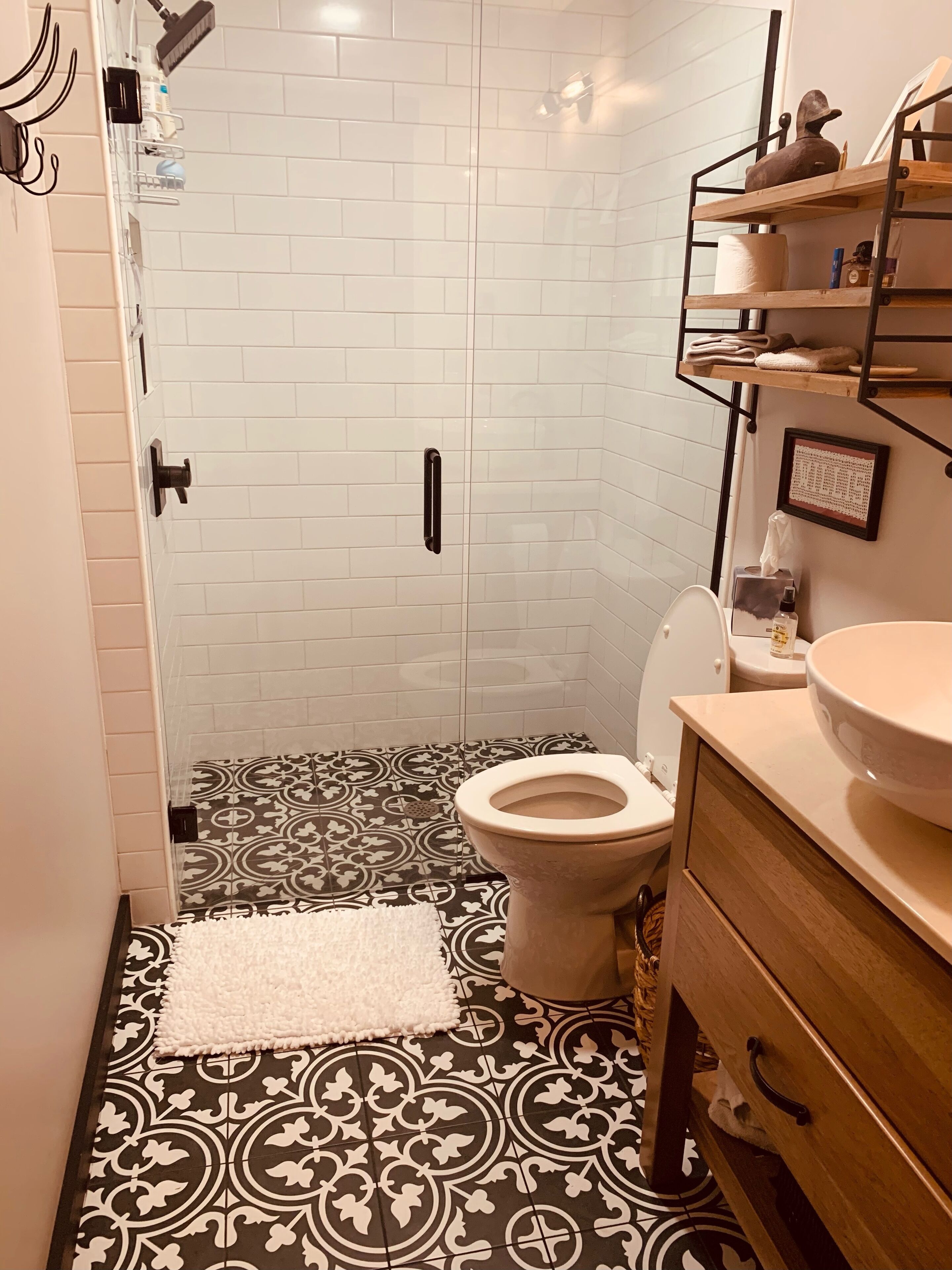 A bathroom with a toilet, a sink, a shower area, and a patterned floor.