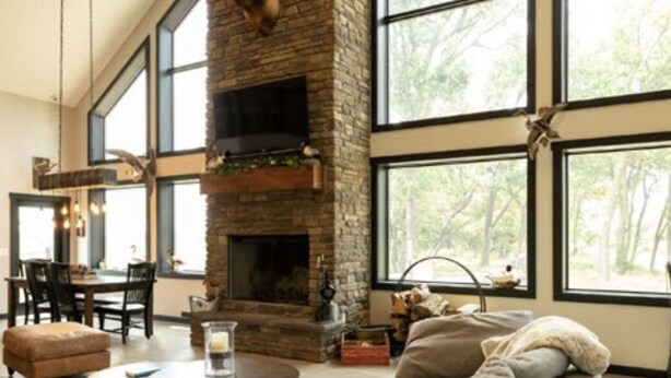 Amplio salón con chimenea de piedra, ventanas grandes y comedor con mesa y sillas.