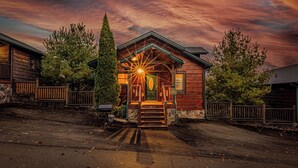 Une cabane en bois dotée d’une véranda, d’une porte d’entrée et d’un escalier menant à l’entrée.