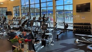 A gym with treadmills, weight machines, and dumbbells.