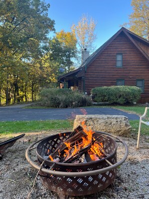 A log cabin with a fire pit in front.